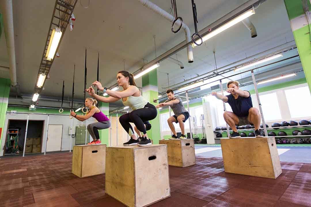group of people doing box jumps exercise in gym